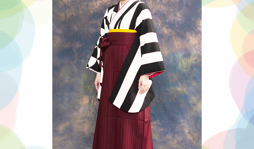 女性袴コレクション15。白と黒の半分がストライプで半分が幾何学柄の着物にエンジ色の縞模様の袴のコーデ