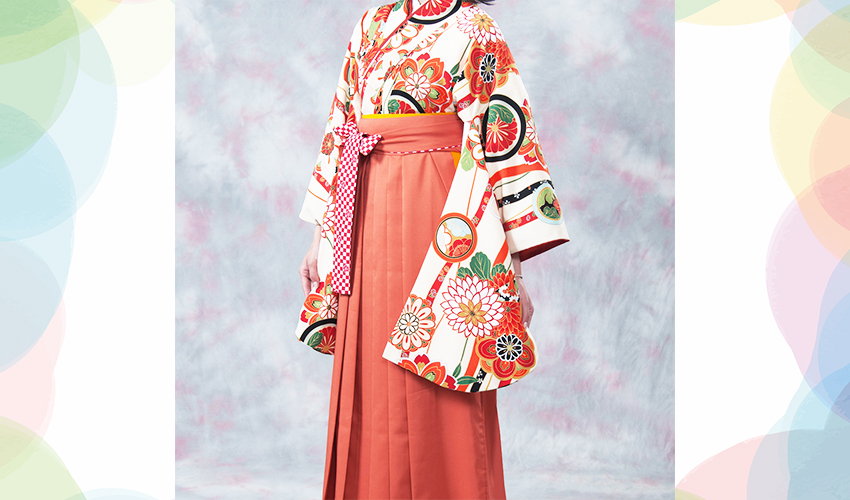 女性袴コレクション2。オフホワイト地のレトロなオレンジ色の柄の着物にオレンジの袴のコーデ