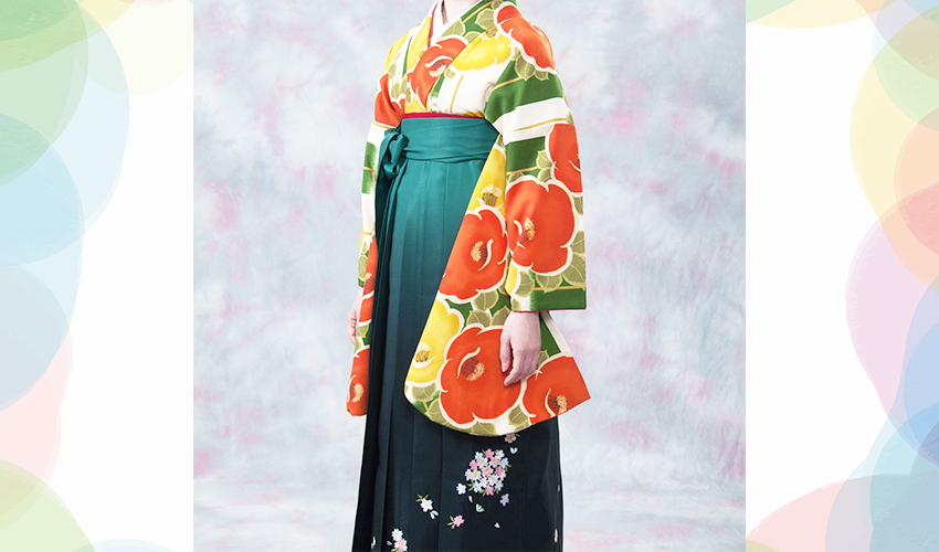 女性袴コレクション20。白とグリン地にオレンジと黄色の椿柄の着物にグリンぼかしの袴のコーデ